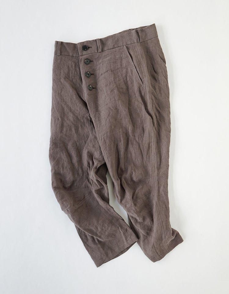 Brown linen women’s trousers laid flat on a white background showing the front with button closure.