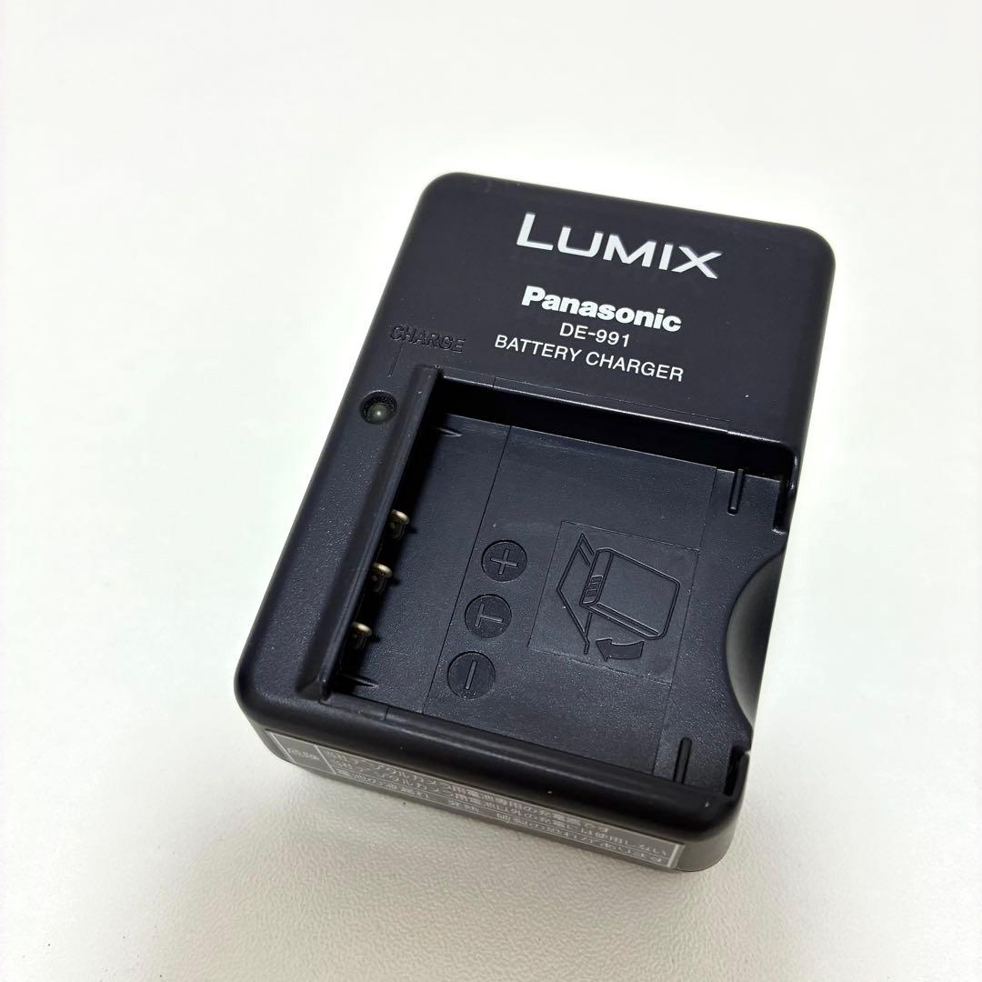 Top view of a Panasonic LUMIX DE-991 battery charger showing the battery slot and LUMIX branding.
