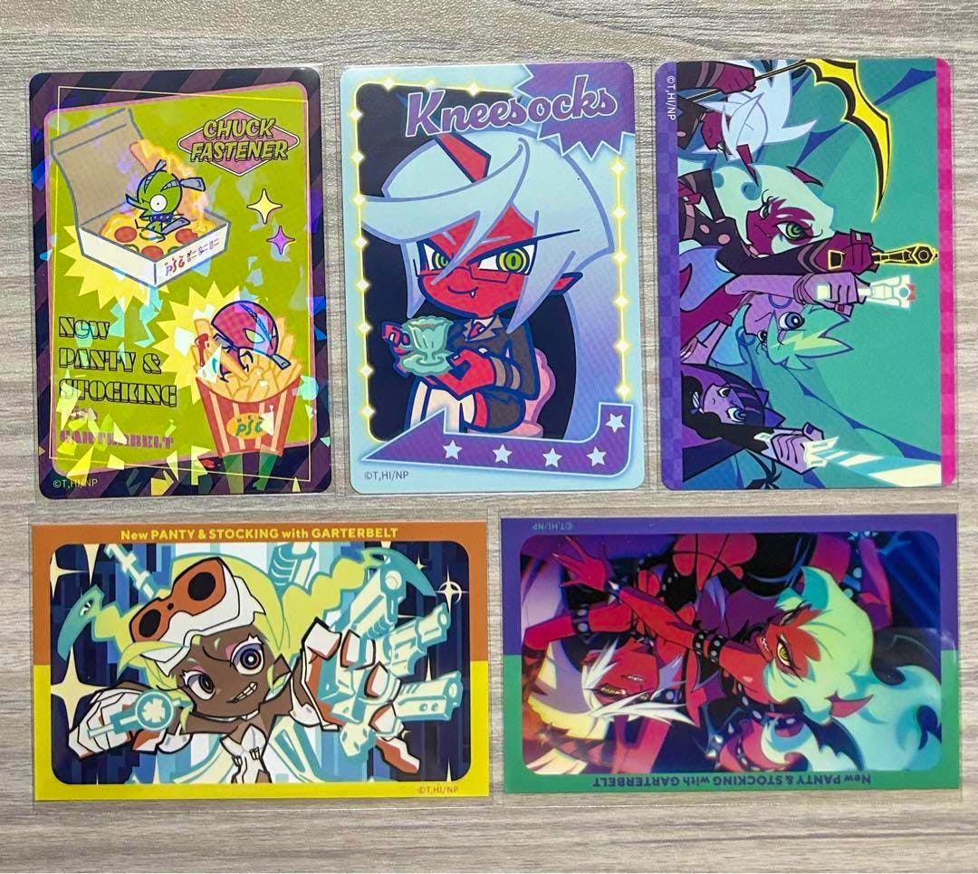 Five Panty & Stocking photocard illustrations arranged on a wooden surface, showing various character artwork.