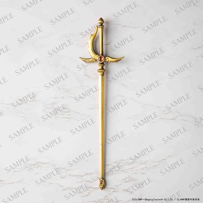 A gold-colored paper knife shaped like a sword on a light marble background.