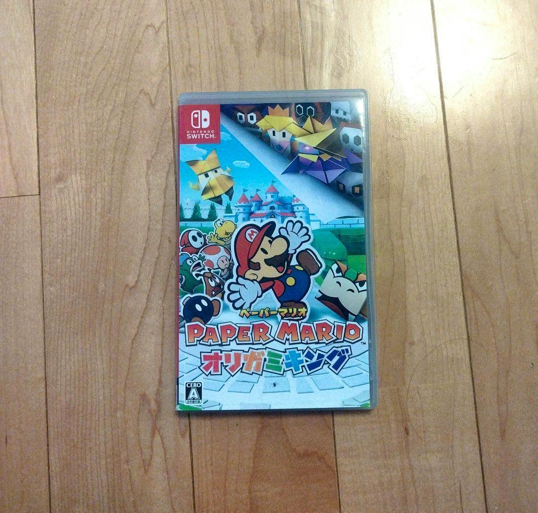 Front cover of the ペーパーマリオ オリガミキング (Paper Mario: Origami King) Nintendo Switch game case lying on a wooden floor.