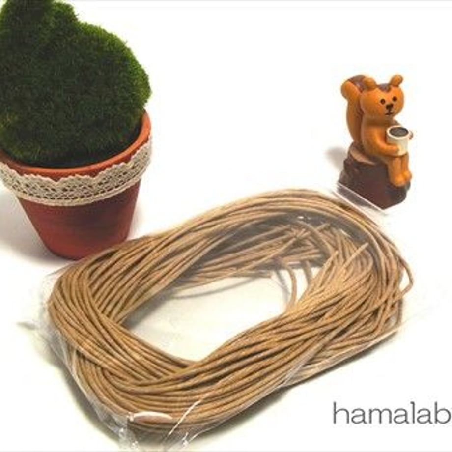 Coiled brown paper twine on a white background displayed with a small potted plant and a squirrel figurine.
