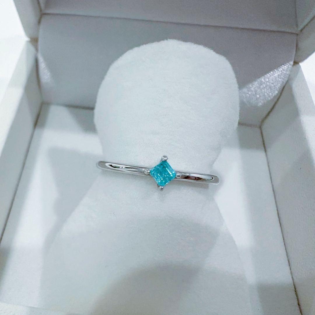 A K18 white gold ring with a square Paraiba tourmaline displayed in a white ring box.