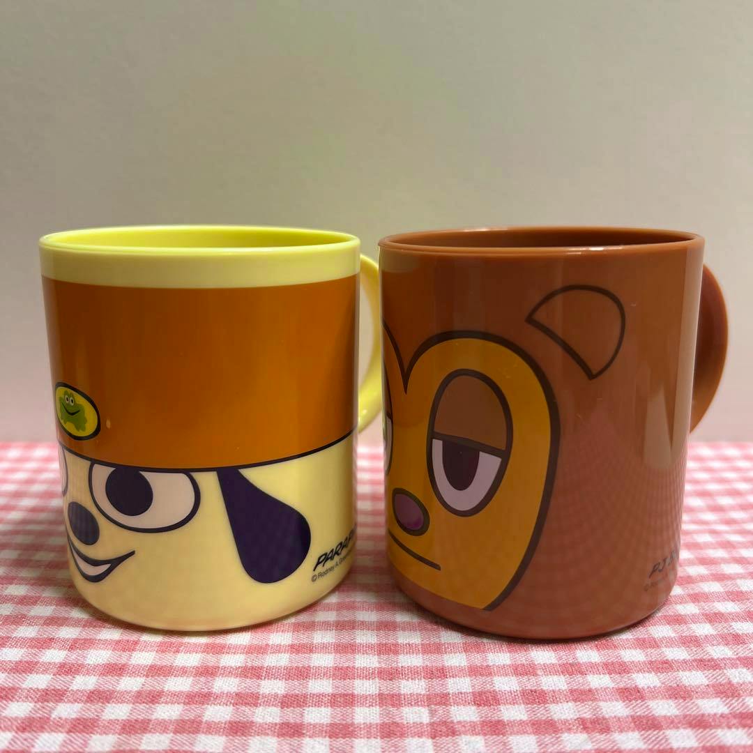 Two Parappa the Rapper (PJ Berry) plastic cups with character faces shown side by side on a pink checkered cloth.
