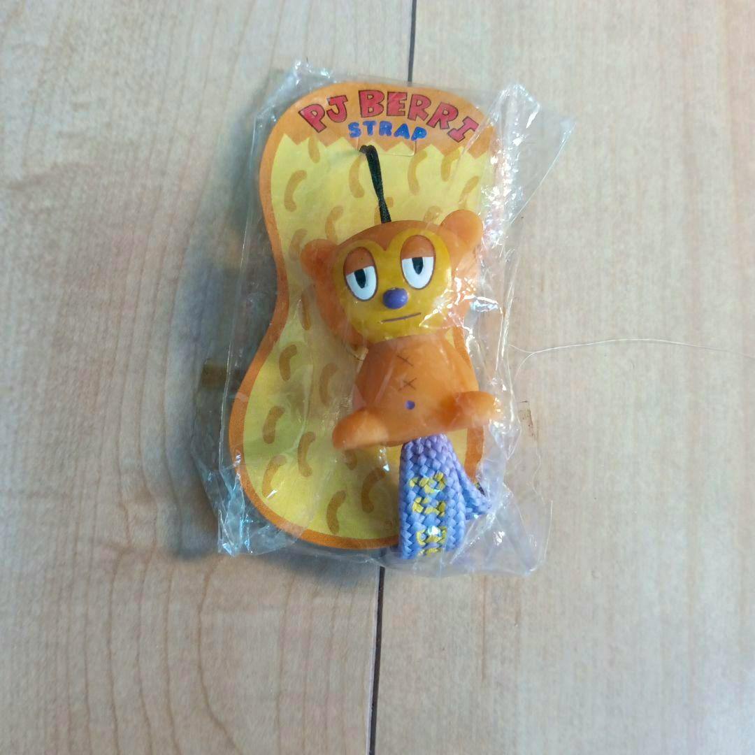 A plastic PJ Berri keychain strap in its clear plastic packaging on a wooden surface.
