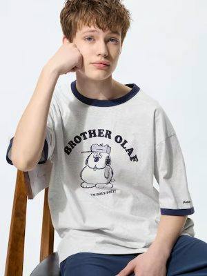 Male model wearing a relaxed-fit men's cotton T-shirt with navy trim and a Peanuts "Brother Olaf" graphic on the front.