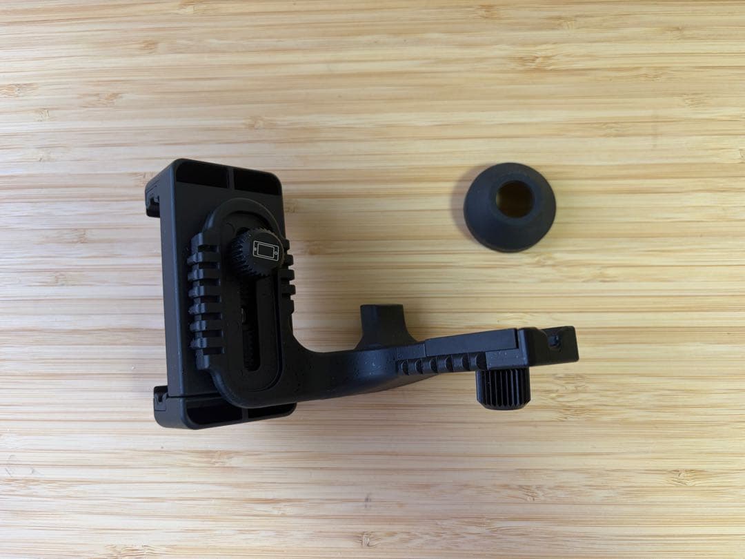 Pentax VM 6×21 WP smartphone adapter (V-SA1) with a separate rubber eyecup on a wooden surface.