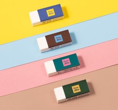 Four Pentel Ain erasers with different colored sleeves arranged diagonally on yellow, blue, pink, and brown backgrounds.