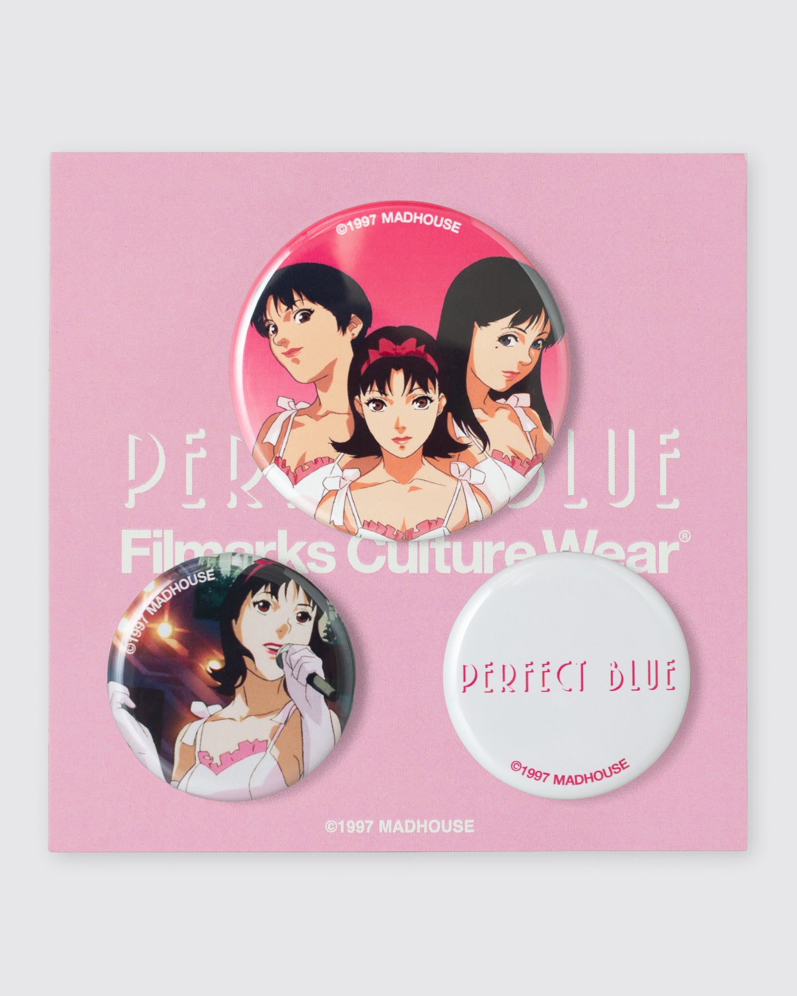 Three round can badges featuring artwork and text mounted on a pink backing card.
