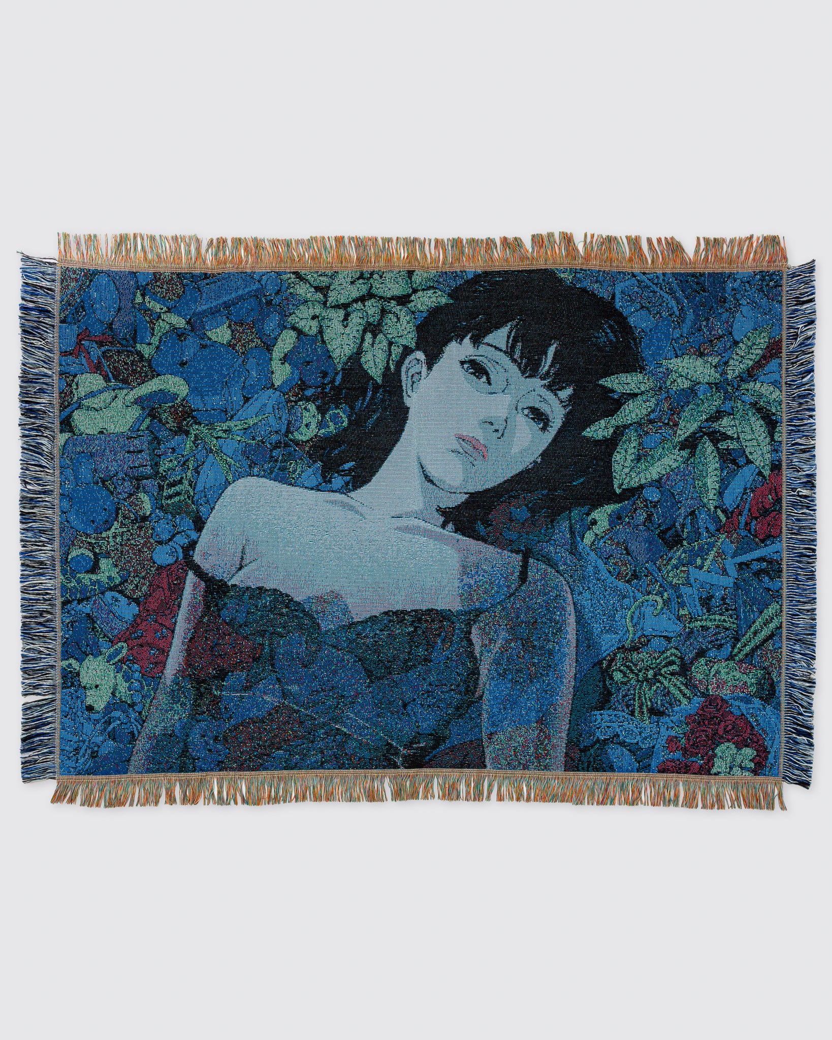 A fringed woven cotton blanket showing an illustrated woman reclining among blue-green foliage.