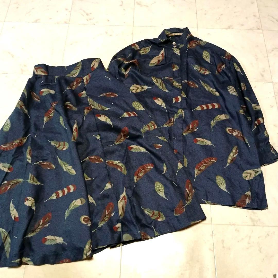 Navy polyester long skirt and long-sleeve blouse set with a feather print laid flat on a tiled floor.
