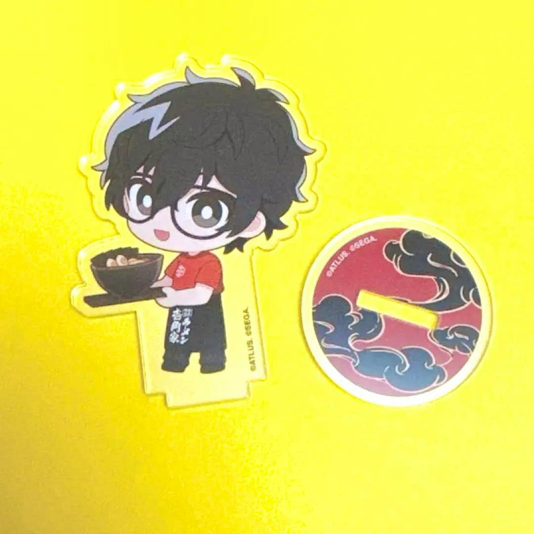 Acrylic stand of Persona 5 protagonist Ren Amamiya in chibi style holding a bowl, with a round printed base shown on a yellow background.