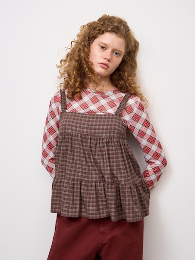Model wearing a brown checked tiered camisole tunic over a red-and-white plaid long-sleeve top, shown from the front.