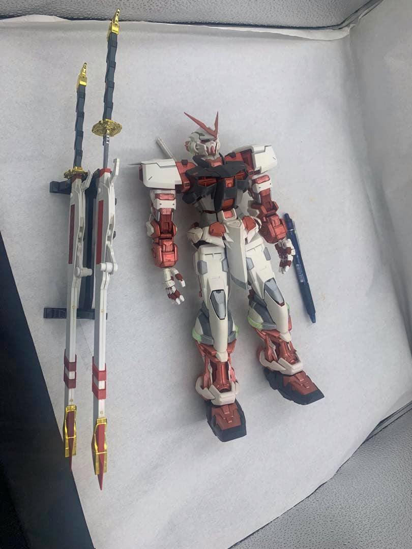 Assembled PG 1/60 Gundam Astray Red Frame Kai model kit (partially painted) lying on a white background with its two swords placed beside it.