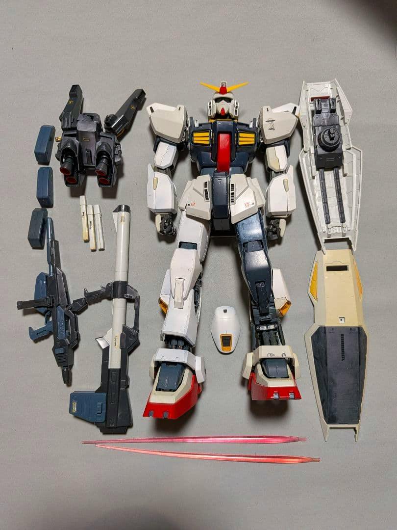 PG ガンダムマーク2 (Gundam Mk-2) model kit parts laid out on a gray background, showing the torso and legs, detached arms, shield, weapons, and two pink beam sabers.