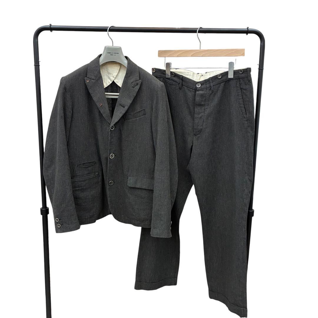 Men's cotton suit jacket and matching trousers hanging on a clothes rack.
