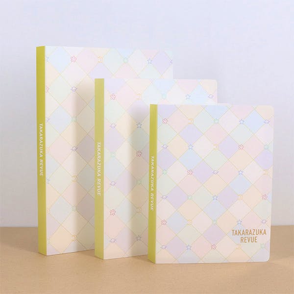 Three pastel-patterned photo holders (photo albums) in different sizes standing on a surface, each showing a diamond pattern and the text "TAKARAZUKA REVUE" on the cover.