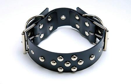 Black synthetic leather collar/harness with metal studs, buckles, and D-rings on a white background.