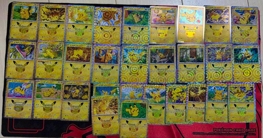 Multiple Pikachu 30th celebration holographic trading cards laid out in rows on a Pokémon playmat.