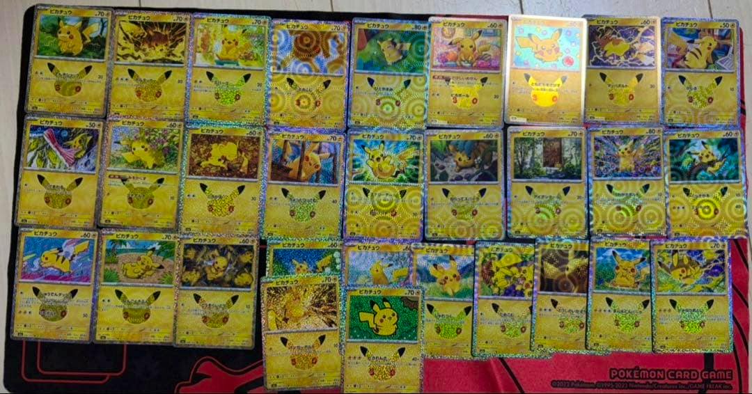 Multiple Pikachu 30th celebration Pokémon trading cards spread out on a playmat.