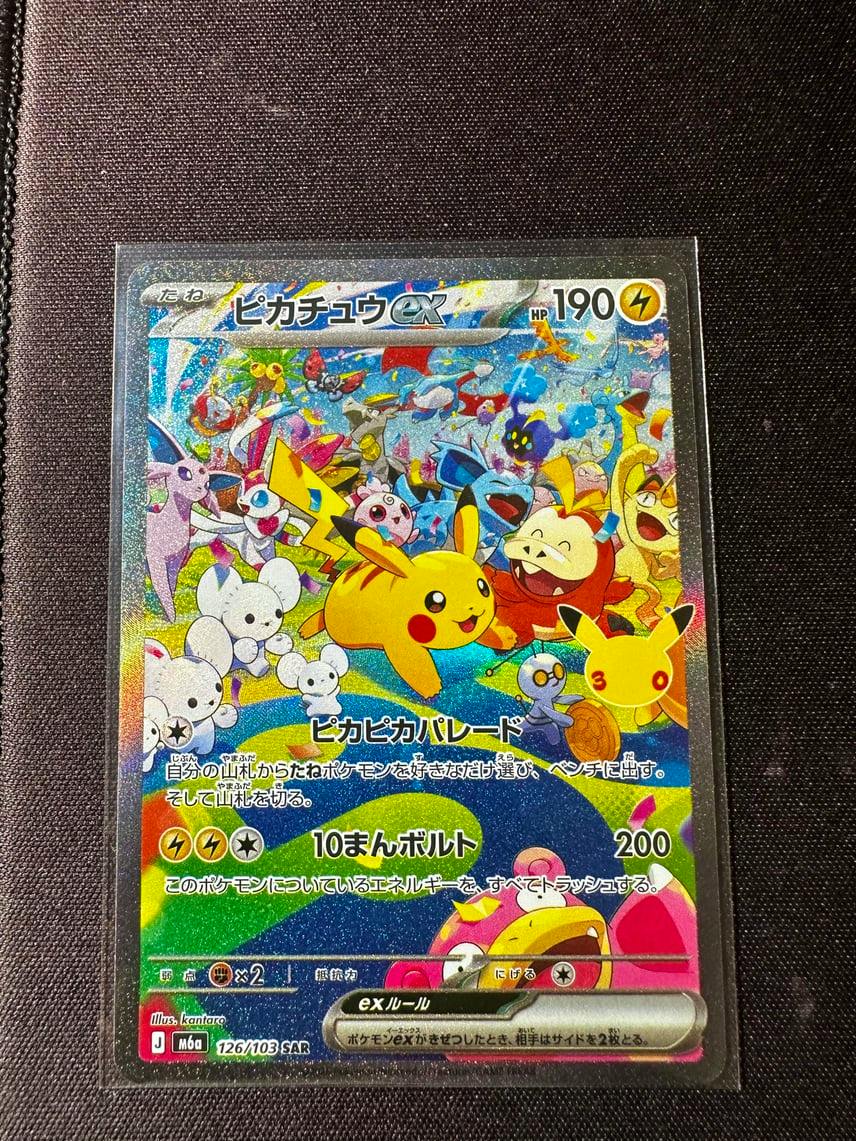 Front of the Pikachu ex trading card showing the holographic colorful artwork and Japanese text, inside a protective sleeve on a dark background.