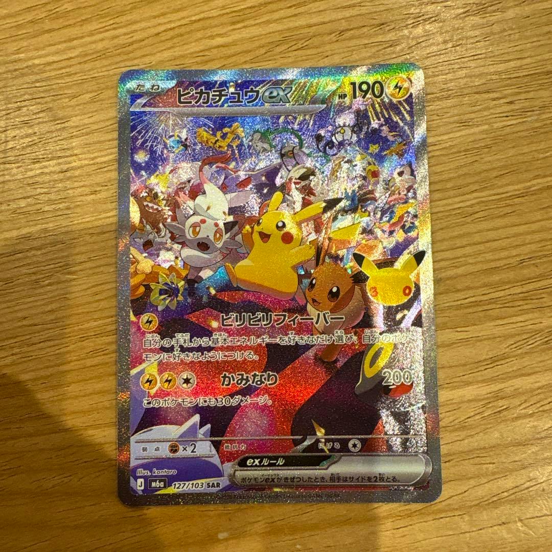 Holographic Japanese ピカチュウex trading card photographed on a wooden surface showing the full card front.