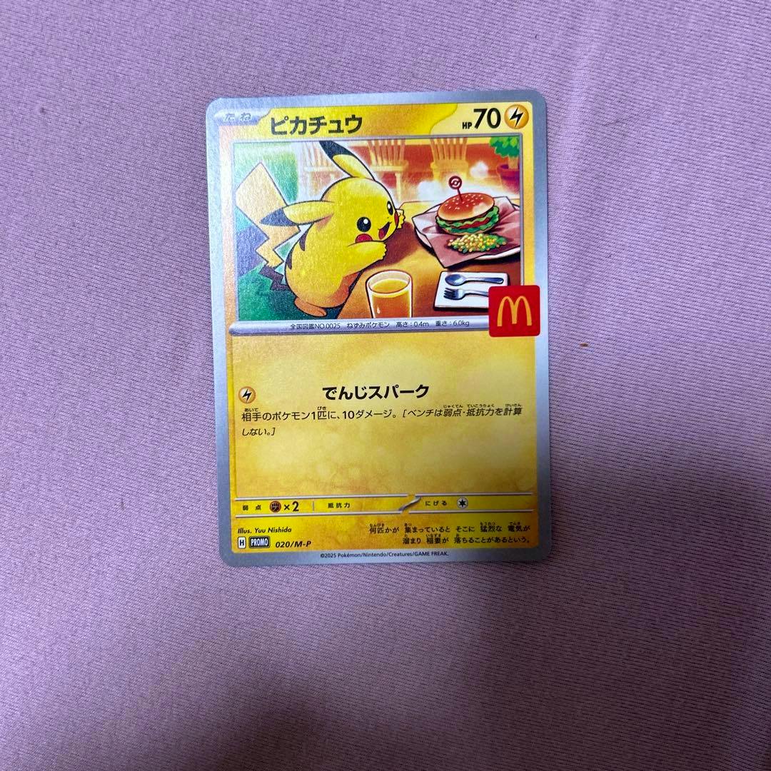 A photo of the Pikachu trading card from the McDonald's Happy Set 2025 lying on a purple fabric background.