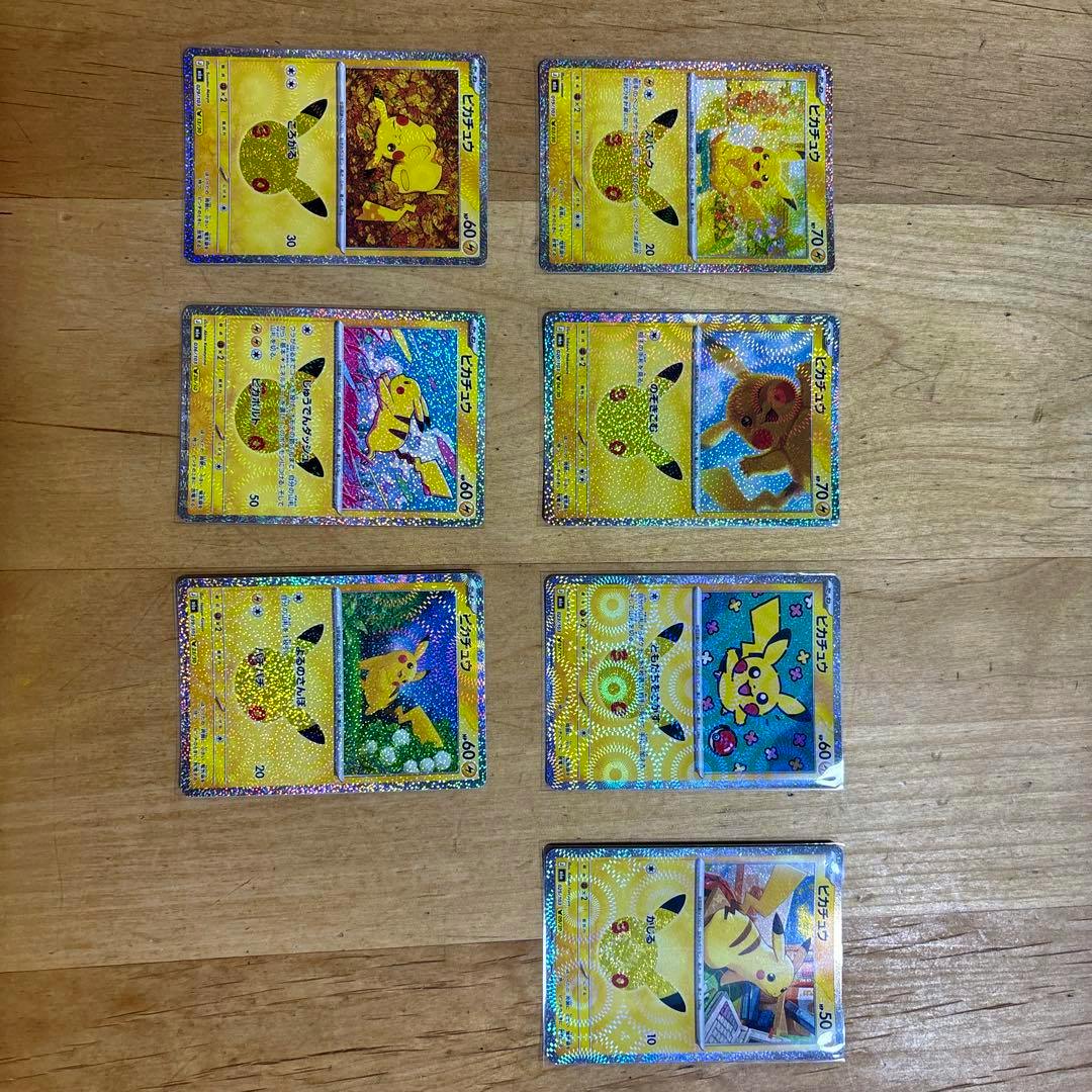 Several holographic Pikachu Pokémon trading cards (fronts) laid out on a wooden surface.