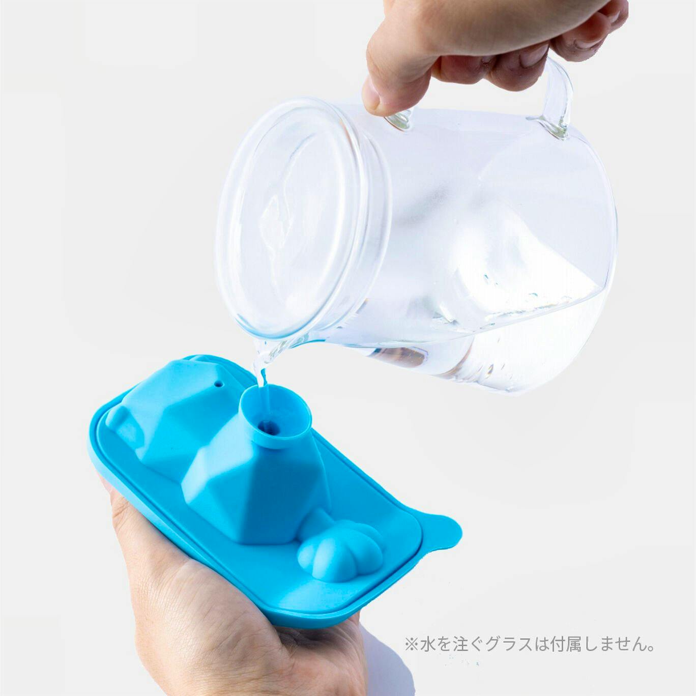 A hand holds a blue silicone ice tray being filled with water poured from a glass.