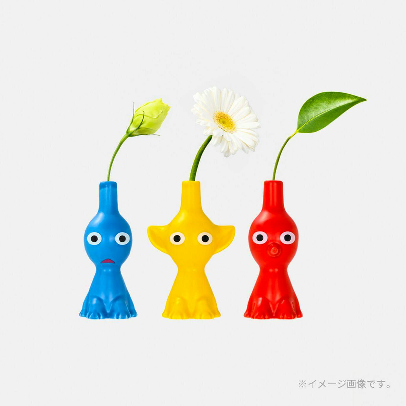 Yellow Pikmin single-stem vase shown center between blue and red Pikmin vases, each holding a single stem flower.