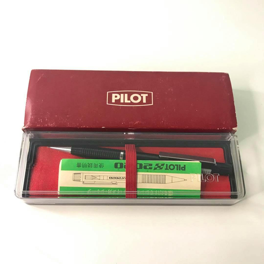 A PILOT 2020 mechanical pencil shown in a clear plastic case with a red inner lining and its red PILOT box.