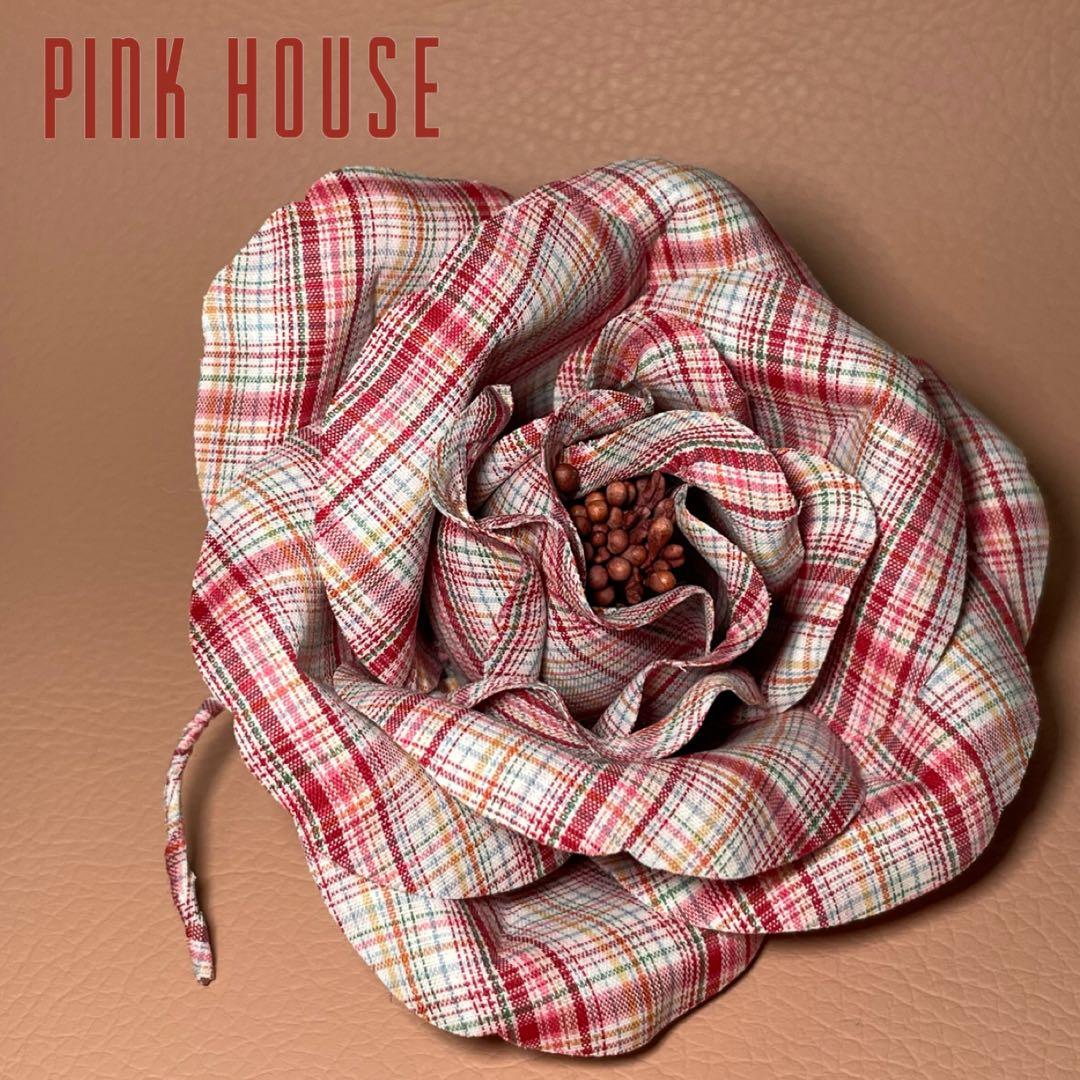 Top-down photo of a polyester checked red rose corsage brooch with a beaded center on a tan background and a 'PINK HOUSE' logo in the corner.
