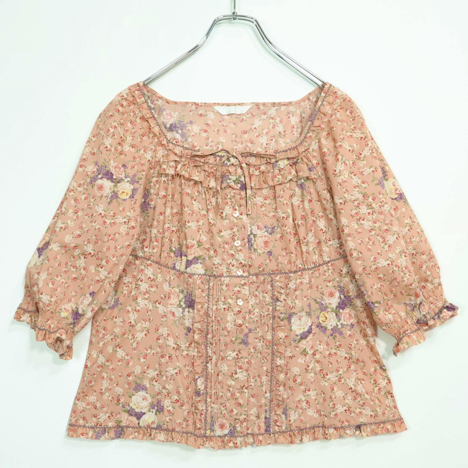 Salmon-pink floral square-neck blouse with ruffled trim and front buttons displayed on a hanger.