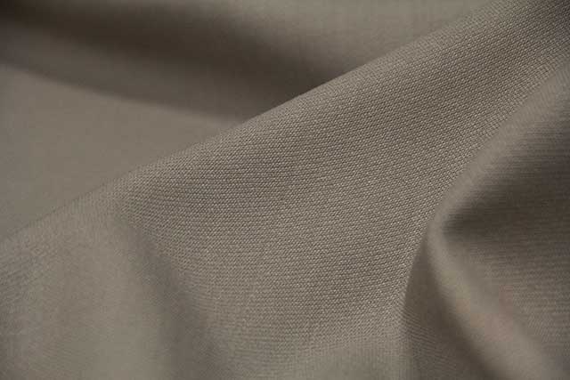 Close-up of a beige-gray wool fabric sample showing its weave and drape.