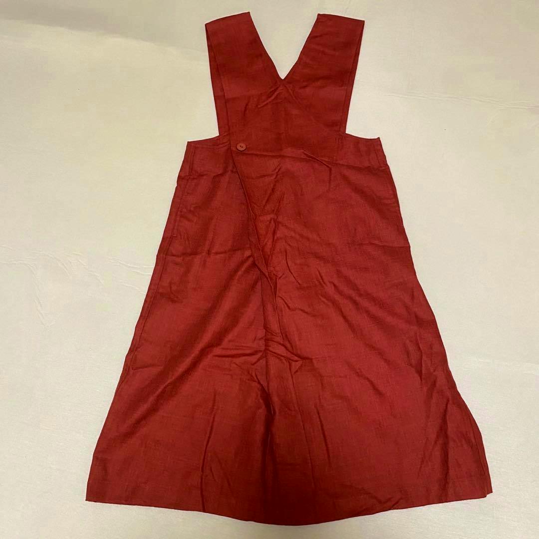 Red wool dress (Plantation ISSEY MIYAKE) laid flat on a light background showing the front with wide V-shaped straps.