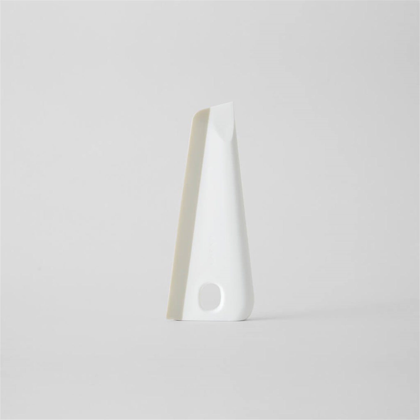 White plastic kitchen spatula standing upright on a plain light background.