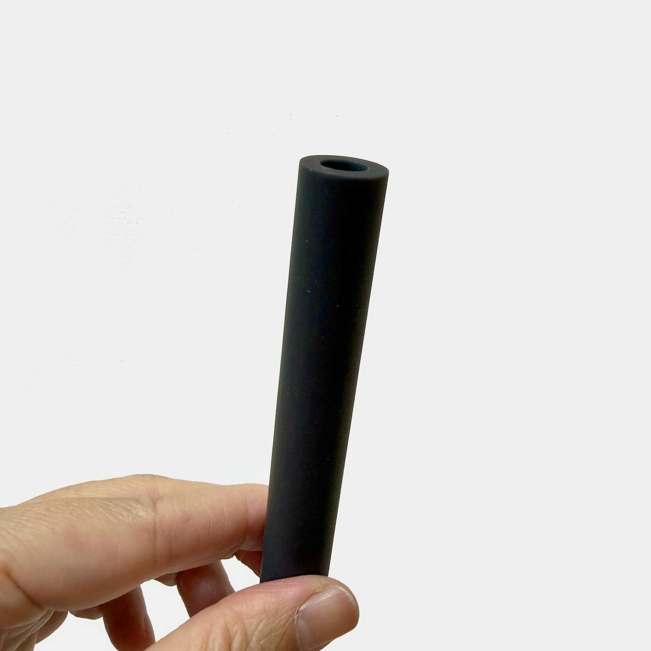 A hand holding a black hollow plastic umbrella rod.