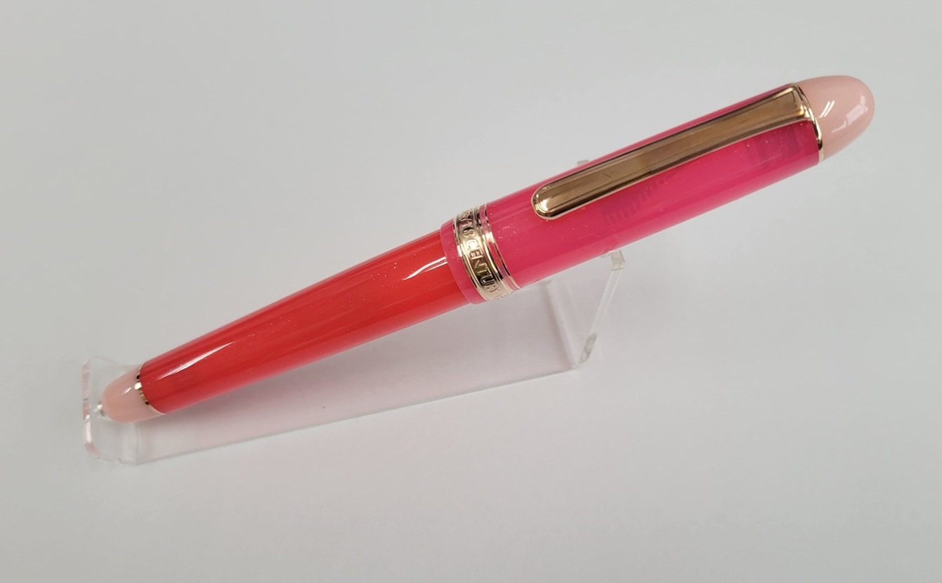 Pink-and-red Platinum #3776 Century "Strawberry Kingdom" fountain pen displayed on a clear stand.