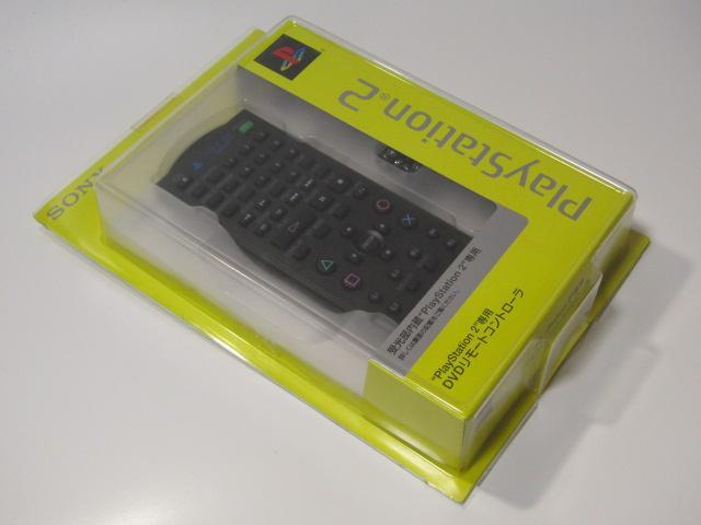 A PlayStation2 DVD remote controller (SCPH-10420) visible inside its yellow retail blister packaging.