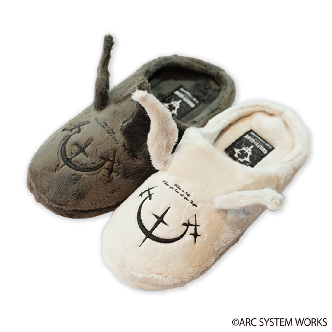 Two plush room slippers (ヴェルファ＆ウェヌス) in beige and dark gray with embroidered face motifs and ear details on a white background.