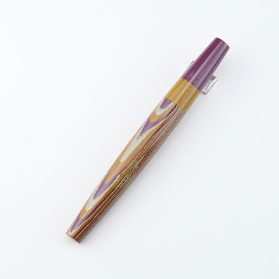 A wooden fountain pen with a purple cap and a patterned wooden barrel on a white background.