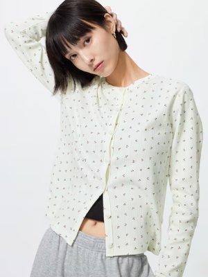 Front view of a light-colored cotton cardigan with a small all-over print worn by a model.
