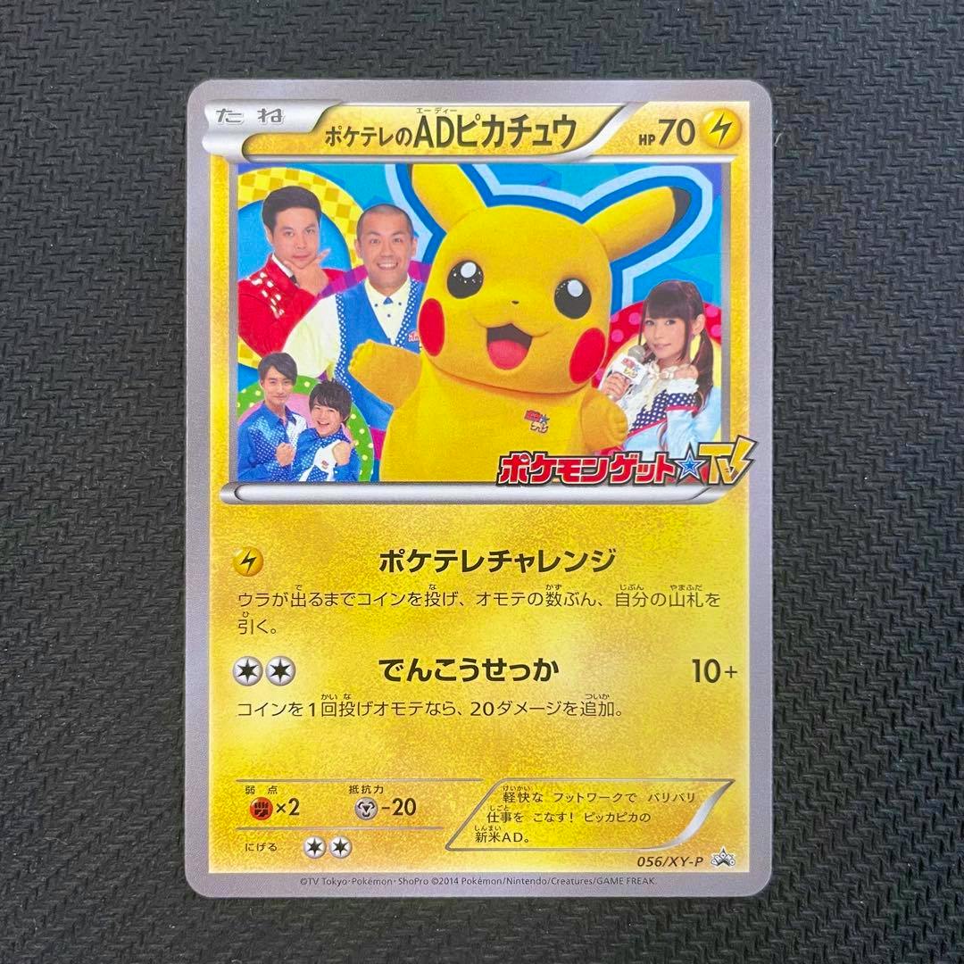 Front of a Pokémon trading card (ポケテレのADピカチュウ) showing Pikachu and TV presenters on a black textured background.