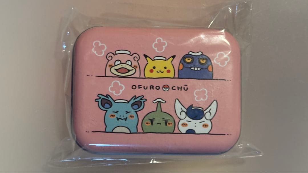 Pink square aluminum tin with Pokémon character illustrations on the lid, shown sealed in plastic.