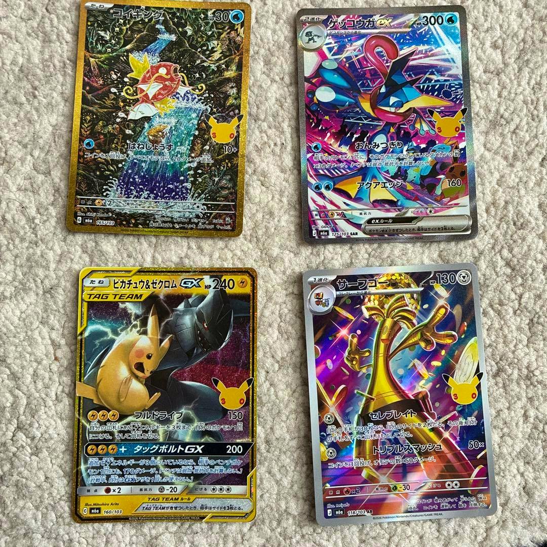 Four Pokémon trading cards laid on carpet showing front artwork, including a コイキング (Magikarp) 30th revival card and three other holo cards.