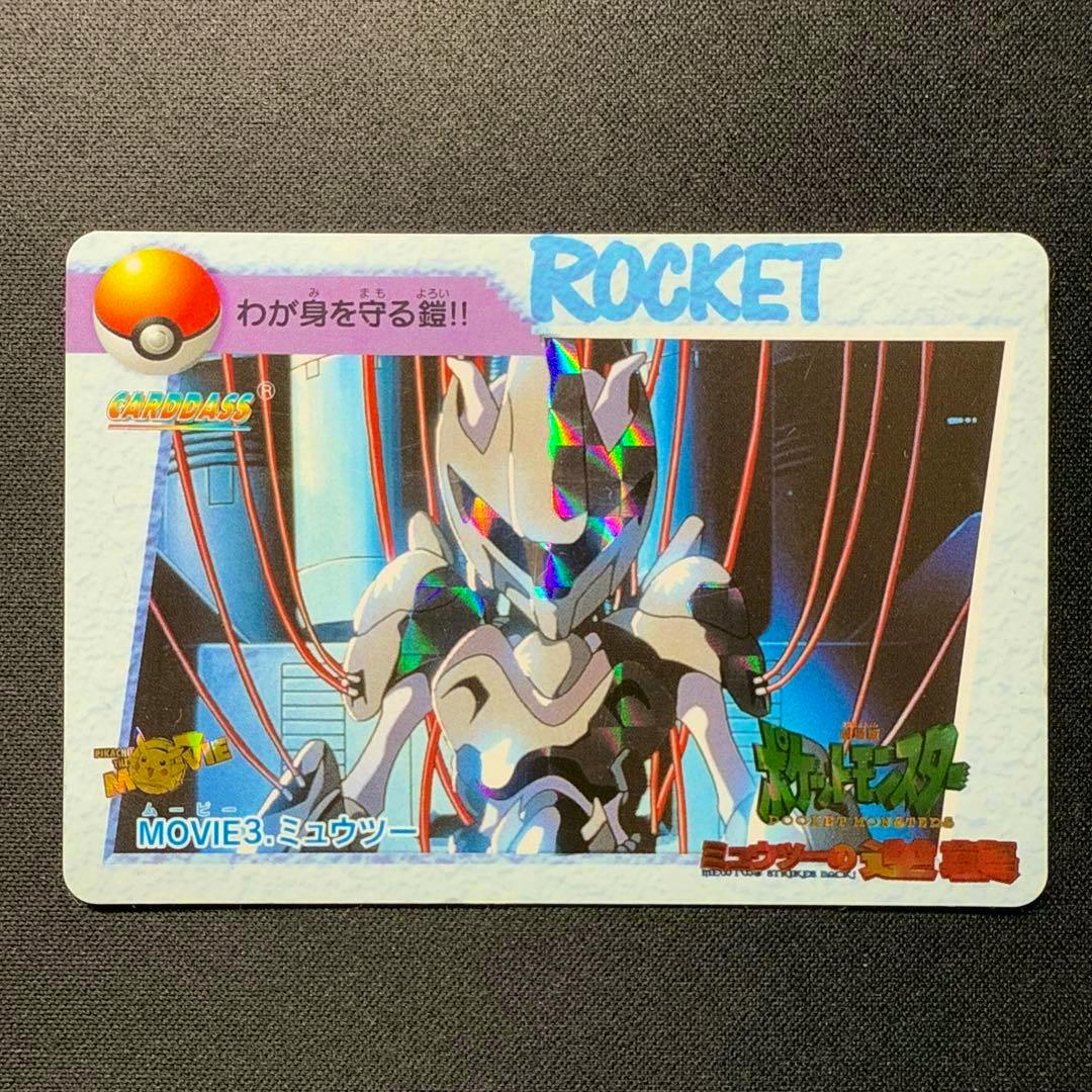 Photocard (ポケモンアニメコレクション movie3 ミュウツー) showing Mewtwo artwork with holographic foil and a "ROCKET" header, photographed on a dark textured surface.