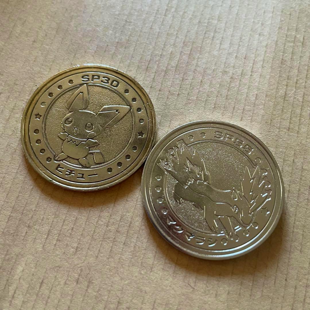 Two Pokémon battle coins featuring Pichu and Magmarashi placed on a cardboard surface.