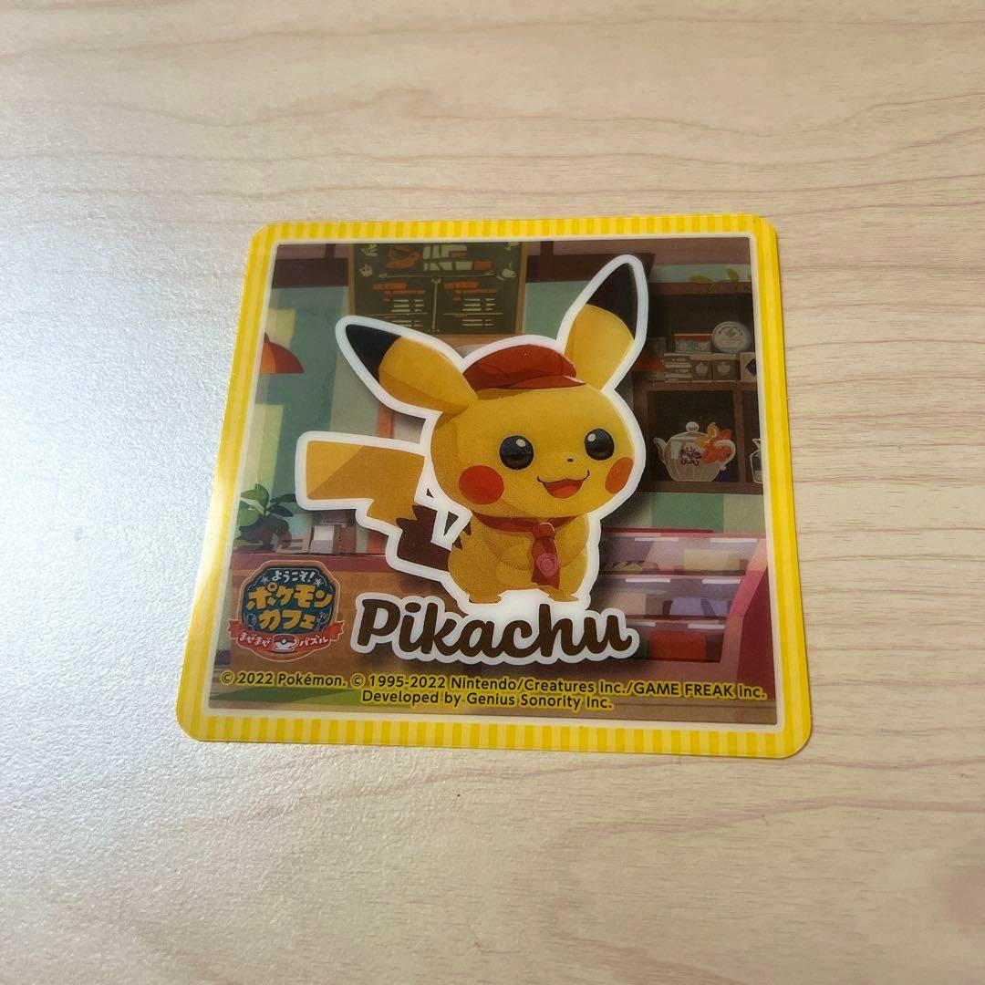 Paper sticker showing a square Pikachu café coaster design with Pikachu and the word "Pikachu" on a wood tabletop.