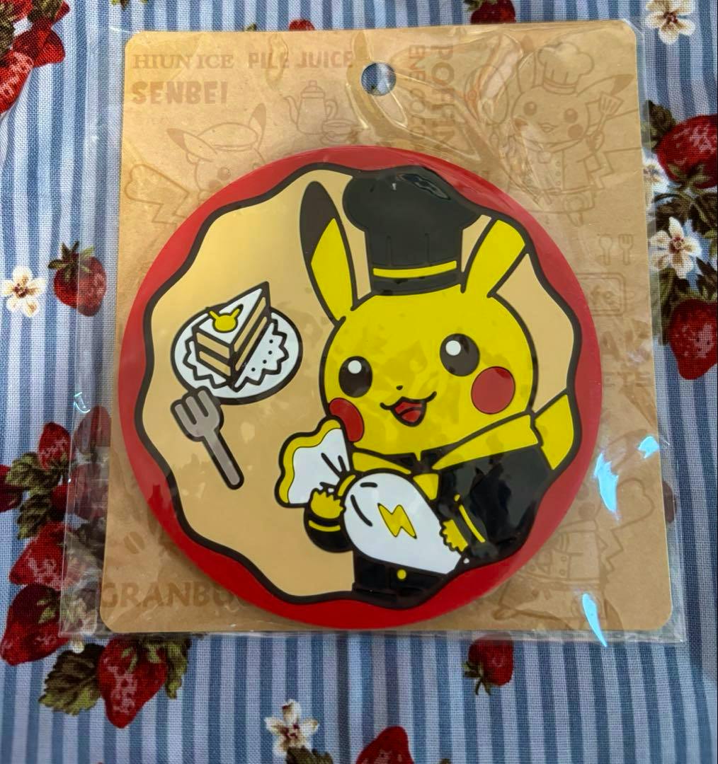 Round rubber coaster showing a chef Pikachu holding a piping bag and a plate with cake, in its original packaging.