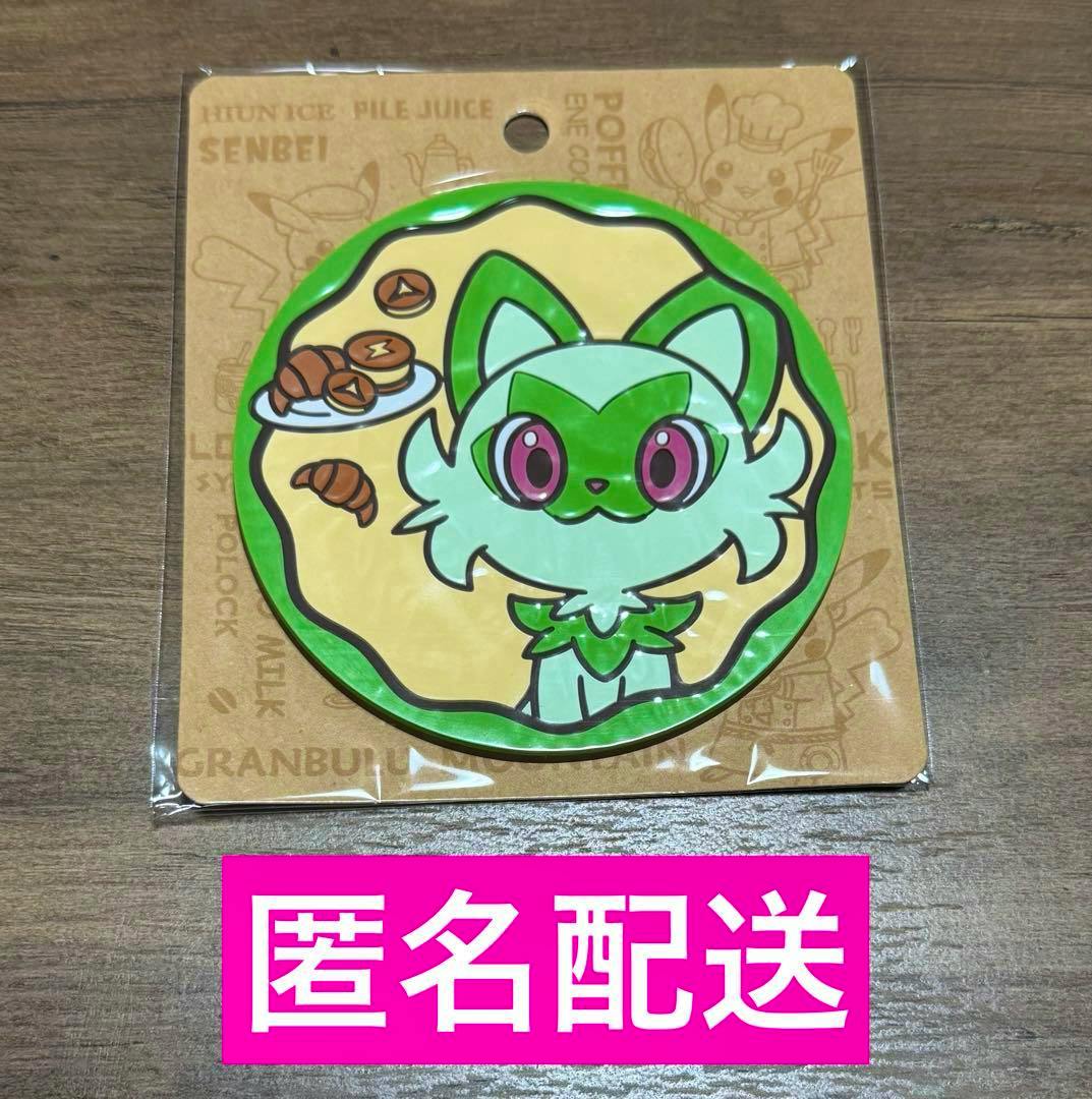 Packaged rubber coaster from the Pokémon Café series showing the green cat-like Pokémon ニャオハ and a small plate of pastries on a round coaster.